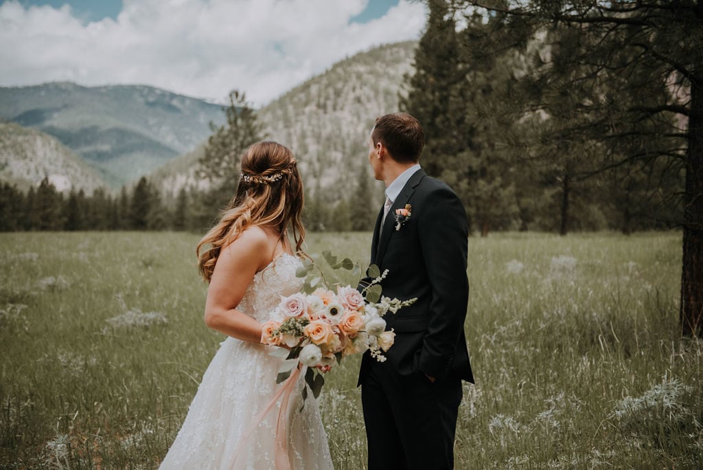 bride and groom looking at a mountain behind them