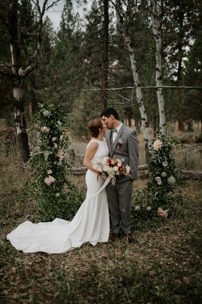 bride and groom kissing in front of arch