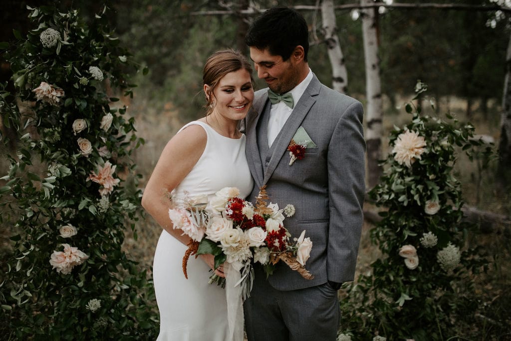 bride and groom embracing in front of arch