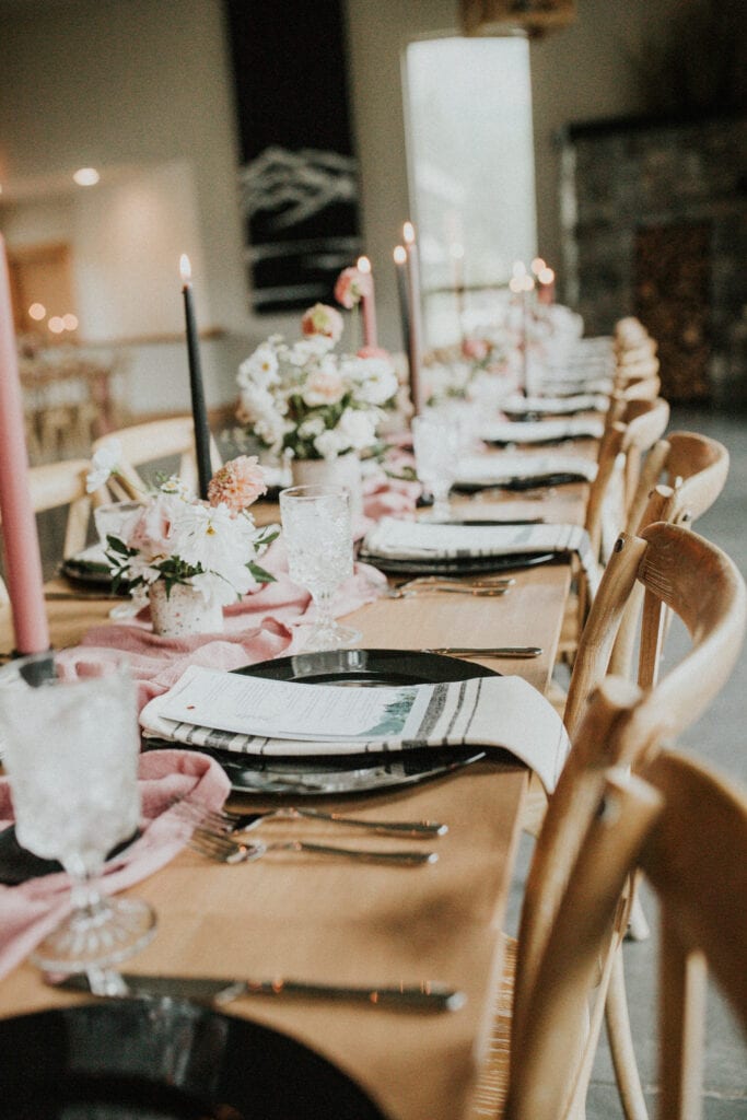 Pink and black table setting with small floral arrangements.